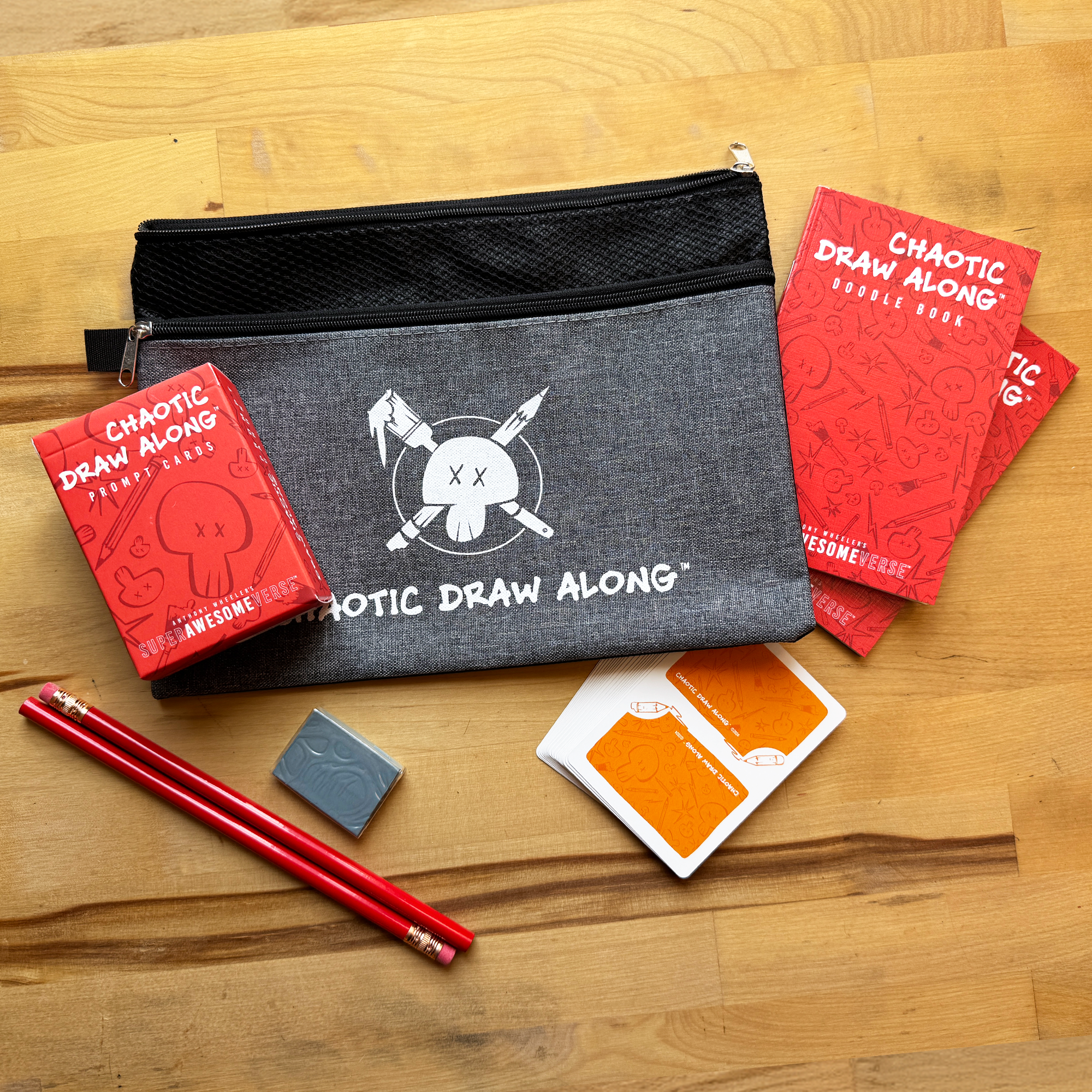 Chaotic Draw Along bundle with prompt cards, doodle books, pencils, eraser, booster cards, and a branded pencil case arranged on a wooden table.