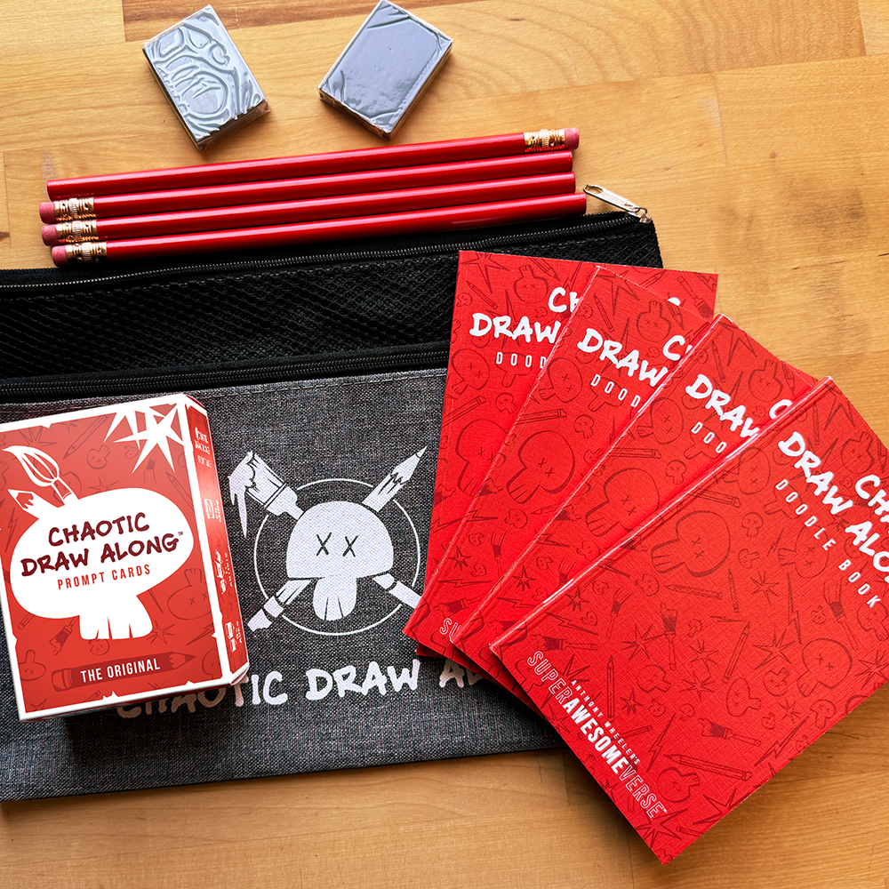 Chaotic Draw Along family night bundle featuring prompt cards, red doodle books, pencils, erasers, and a branded pencil case arranged on a wooden table.