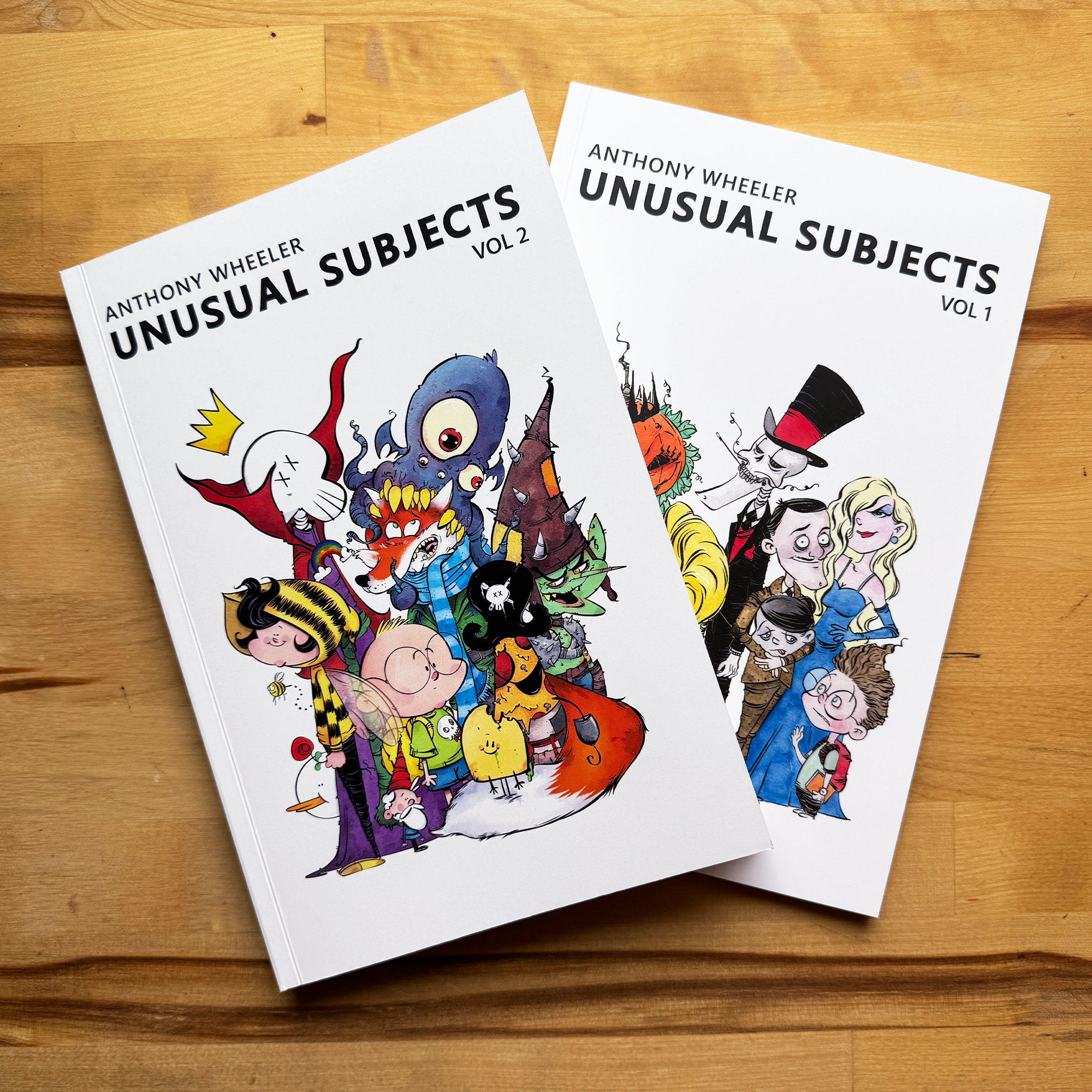 Anthony Wheeler’s Unusual Subjects Vol. 1 and Vol. 2 art books displayed together on a wooden tabletop.