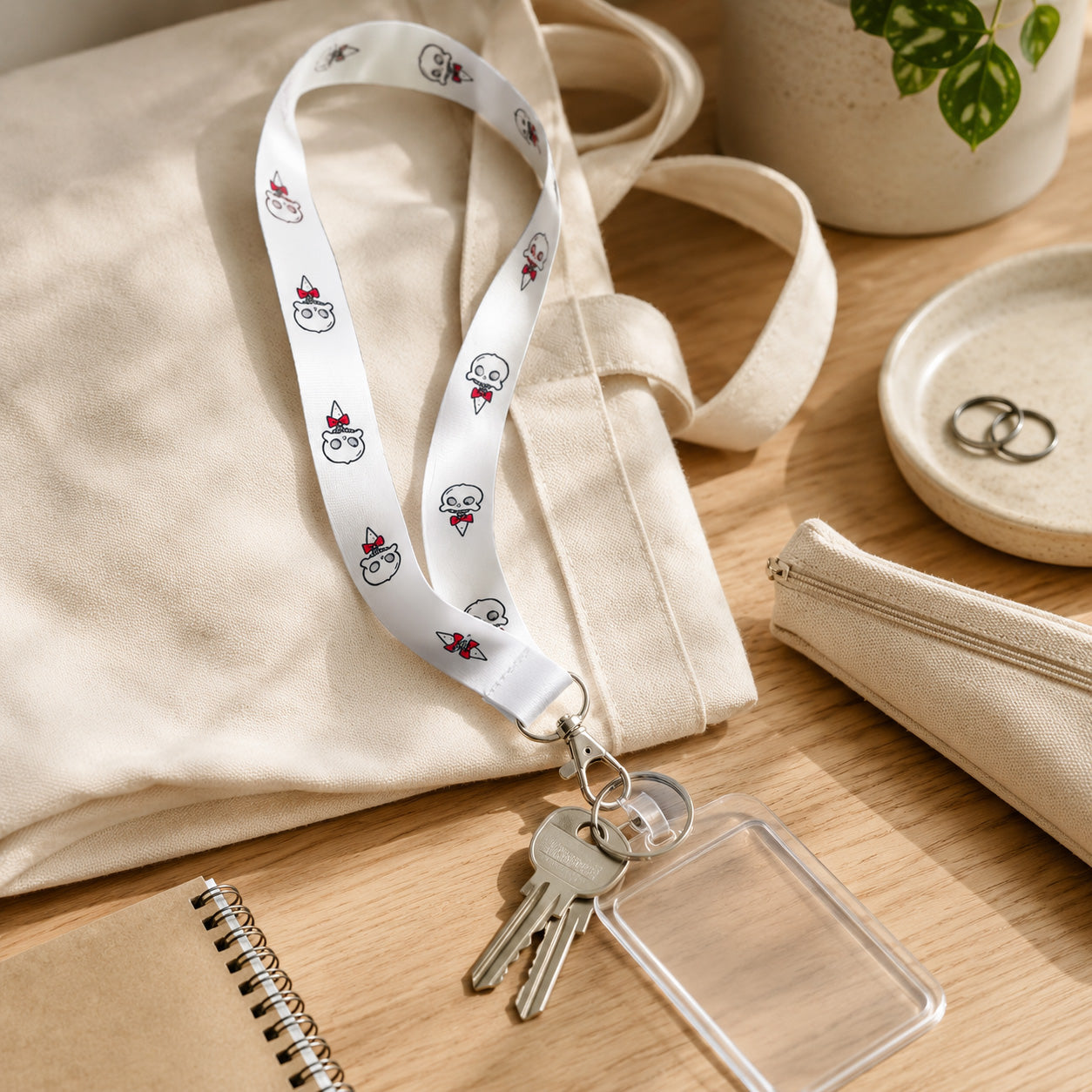 Wally lanyard clipped to keys and a clear ID badge holder on a canvas tote bag, showing the secure silver metal attachment.