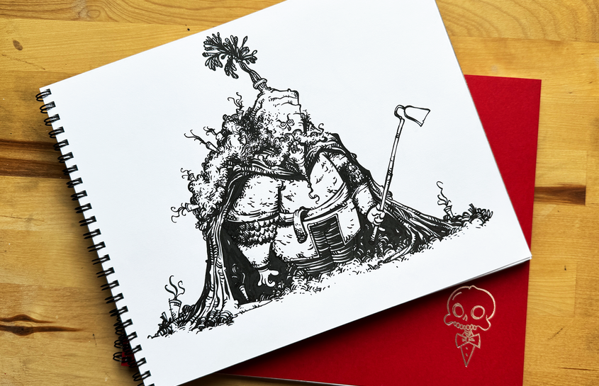Open sketchbook with a detailed black ink character drawing on a wooden table, layered over a red Chaotic Draw Along sketchbook cover.