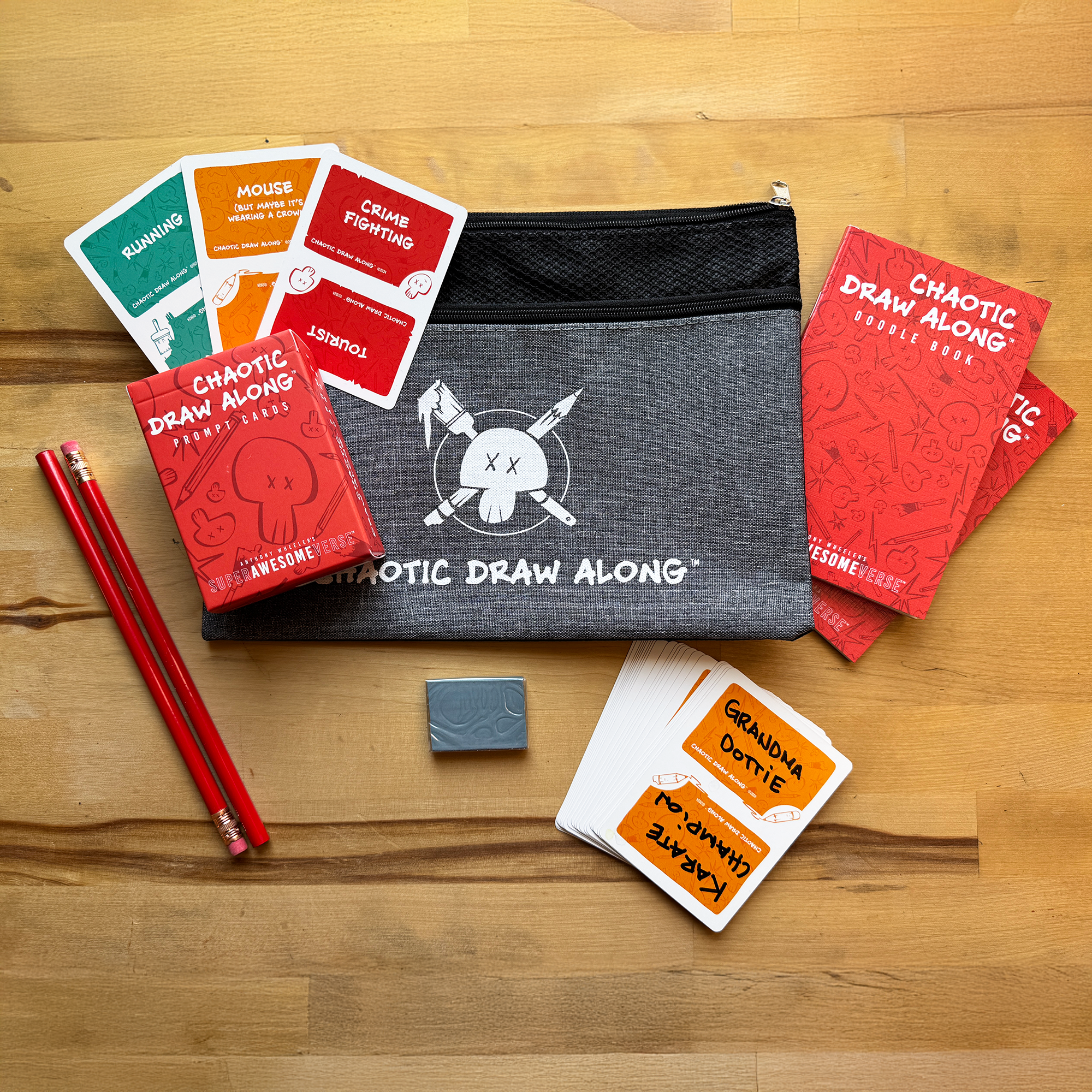 Chaotic Draw Along everything-you-need bundle with prompt cards, doodle books, booster cards, pencils, eraser, and a branded pencil case on a wooden table.