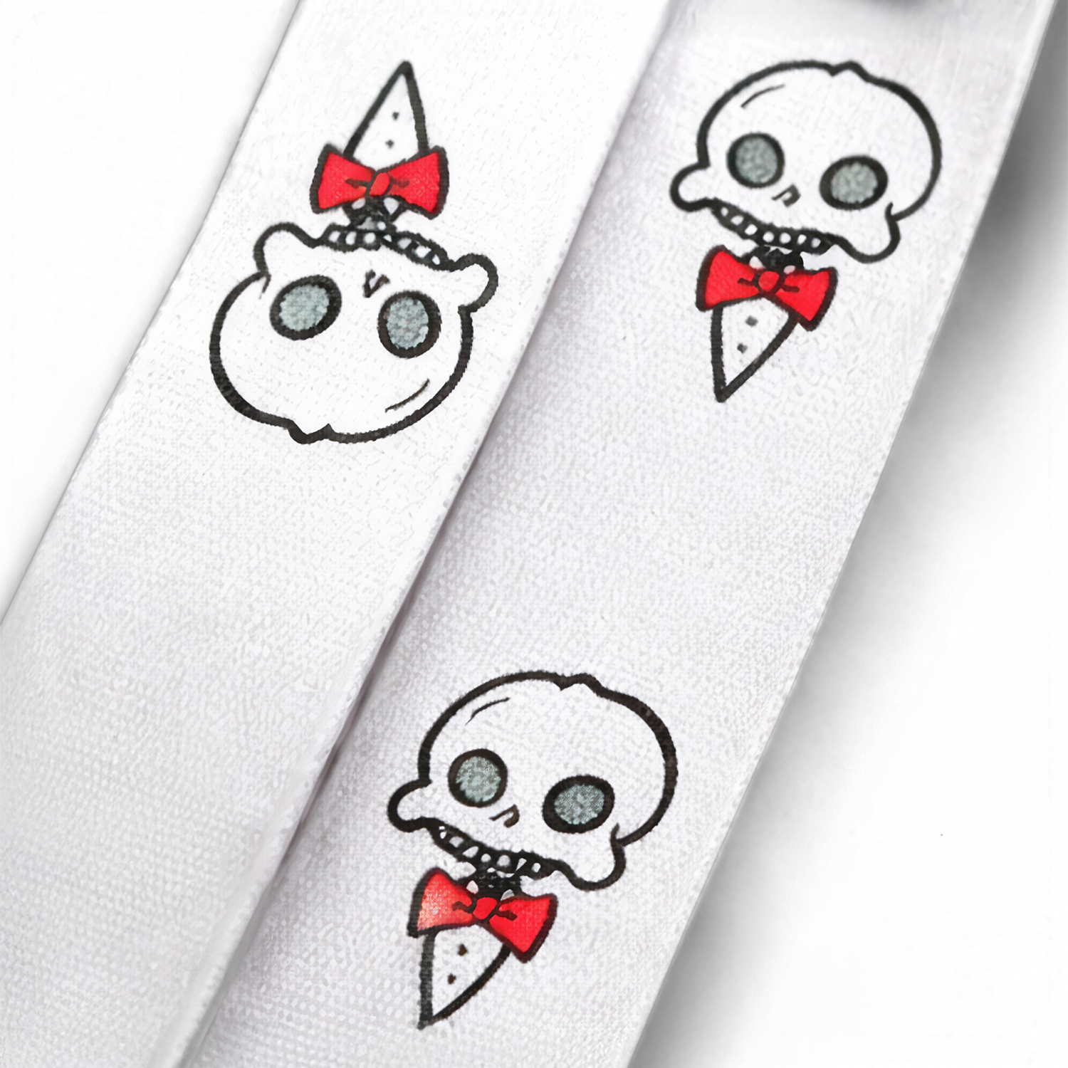 Close-up of the Chaotic Draw Along white skull lanyard showing red bow tie character artwork printed on the fabric.